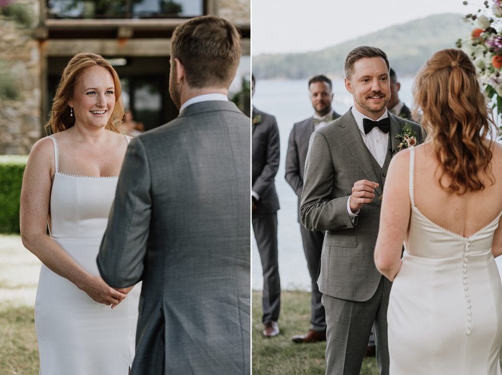 A bride and groom stand outdoors during their wedding ceremony, facing each other and exchanging vows. The groom is holding a ring.