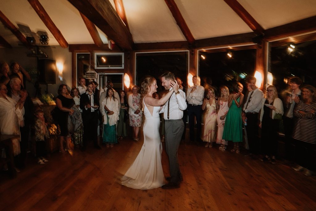 A man and woman dancing in a room with people watching.